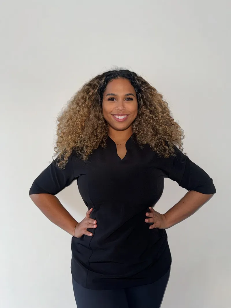 Rebecca, oprichter van Body Contour Clinic Almere, staand in zwart shirt tegen een witte achtergrond