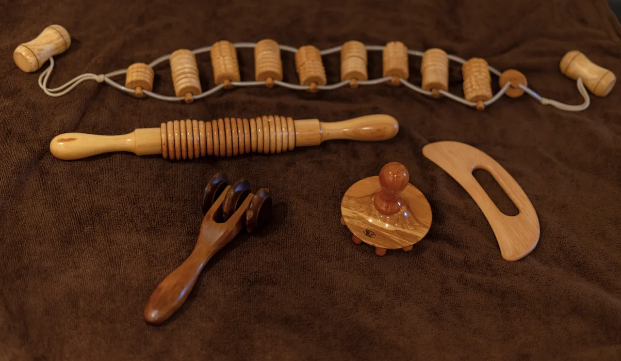 Houten maderotherapie-instrumenten uitgestald op een bruine doek