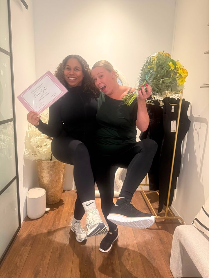 Twee lachende cursisten vieren het behalen van hun certificaat in de salon